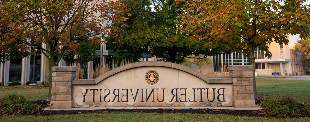 concrete sign with words Butler University and trees behind it